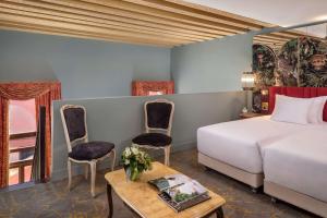 una camera con letto, sedie e tavolo di NH Collection Grand Hotel Palazzo Dei Dogi a Venezia