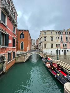 a bridge over a canal in a city with two boats at Hotel Alla Fava in Venice