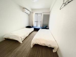 - 2 lits dans une petite chambre avec fenêtre dans l'établissement SIMPLY WHiTE GUEST ROOM302, à Osaka