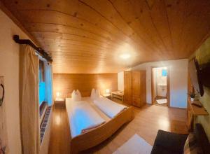 Schnann的住宿－Pension Bucher，一张位于带木制天花板的客房内的大床