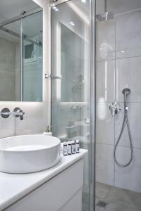 biała łazienka z umywalką i prysznicem w obiekcie Urban Heights 3BD Apt, next to Hilton w Atenach