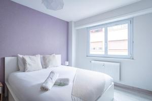 um quarto com uma cama branca com uma toalha em Le Lys - Wifi - 10 min centre ville em Estrasburgo