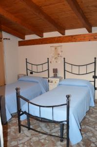 2 camas en una habitación con techos de madera en Giardino degli Ulivi, en Gonnesa