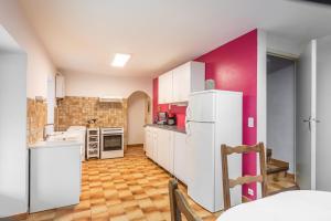 eine Küche mit weißen Geräten und einer rosa Wand in der Unterkunft L'Espedes in Ruoms