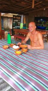 a man sitting at a table with a plate of food at Rosa Shashi Cabanas in Galle