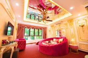 uma grande sala de estar com um grande sofá rosa e cadeiras em King's Hotel Linh Đàm 1 em Hanói