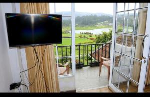a flat screen tv in a room with a balcony at Medalin Lake Gregory in Nuwara Eliya