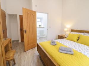 a bedroom with a yellow bed with towels on it at 3 Mountain View in Llangefni