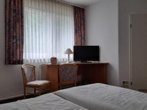 a bedroom with a bed and a desk with a television at Pension Landhaus Machold in Friedrichroda