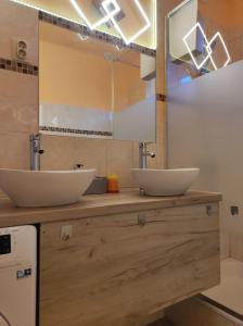 two sinks on a wooden counter in a bathroom at Jázmin Apartman in Szeged