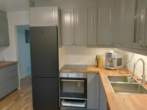eine Küche mit einem schwarzen Kühlschrank und einer Spüle in der Unterkunft Modern villa near Gothenburg in Göteborg