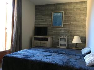 une chambre avec un lit bleu et une télévision dans l'établissement Chalet rénové 7 pers, 2 chambres, parking, animaux admis - FR-1-504-68, à Saint-Étienne-en-Dévoluy