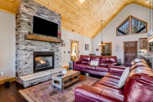 a living room with leather furniture and a stone fireplace at Rustic Retreat in Ellijay