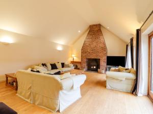 sala de estar con 2 sofás y chimenea en The Stables at Hall Barn, en Diss