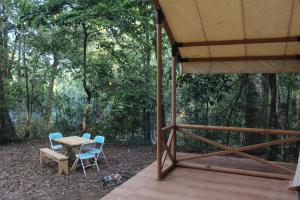a table and chairs on a porch with a tent at ELA Glamping Madikeri in Madikeri