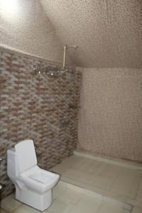 a bathroom with a toilet and a brick wall at ELA Glamping Madikeri in Madikeri