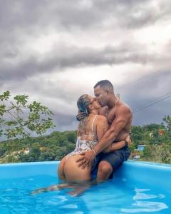 a man and woman sitting on the edge of a swimming pool at Pousada Amazônia Encantada in Iranduba