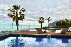 a swimming pool with two chairs and palm trees at Peaceful Madeira Palace in Funchal