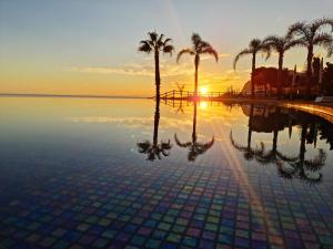 a pool with palm trees and a sunset in the background at Peaceful Madeira Palace in Funchal