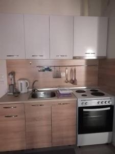 a kitchen with white cabinets and a stove and a sink at City Center Beauty in Serres