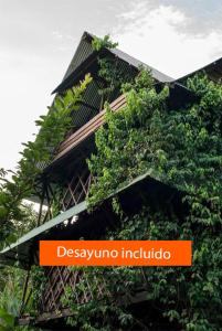 un edificio cubierto de plantas con un letrero naranja. en Ayahuasca en Puerto Nariño