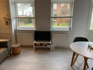 een woonkamer met een tv en een tafel en ramen bij De Nollen in Egmond aan den Hoef