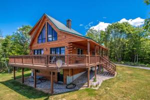 uma cabana de madeira com um grande deque num relvado em The Hive at Blue Spruce Lodge White Mnts View em Brownfield