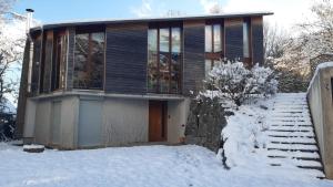 a house in the snow with a snow covered driveway at Gîte du Kiwi in Luttenbach-près-Munster