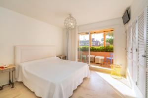 a white bedroom with a bed and a window at Houmi Sotogrande in Sotogrande