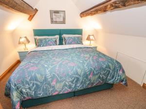 1 Schlafzimmer mit einem Bett mit blauer Bettdecke und 2 Lampen in der Unterkunft Keepers Cottage in Ludlow