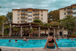 una mujer sentada en la piscina de un hotel en Departamento de lujo en la playa, en Jacó