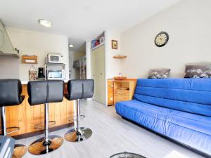 eine blaue Couch in einem Wohnzimmer mit einer Uhr an der Wand in der Unterkunft Studio Morzine, 1 pièce, 6 personnes - FR-1-524-104 in Morzine