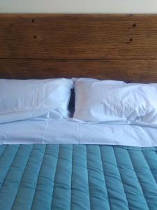 Una cama con sábanas blancas y almohadas. en Villa Sol en Córdoba