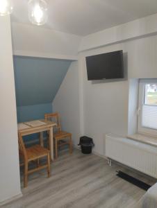 Habitación con mesa y TV en la pared. en Agroturystyka u Pawła i Asi, en Kobyla Góra