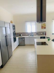 una cocina con electrodomésticos de acero inoxidable y armarios blancos en Relax Serviced Ocean 3bedroom Beach Front House, en Bijilo