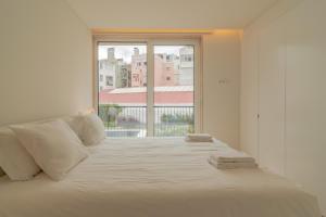 a white bed in a room with a large window at Bright 1 BDR Apartment W/ Pool View by LovelyStay in Lisbon