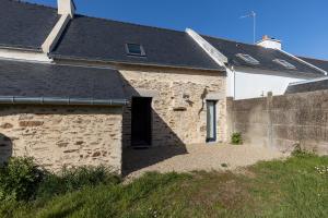ein altes Steinhaus mit schwarzem Dach in der Unterkunft Penty - Charmante maison rénovée 50m de la mer à Banastère in Sarzeau