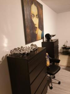 eine Kommode und ein Stuhl in einem Zimmer mit einem Gemälde in der Unterkunft Ferienwohnung Ebbe in Attendorn