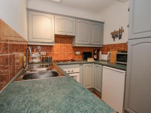 a kitchen with white cabinets and a stainless steel sink at 26 High Street in Bishops Castle