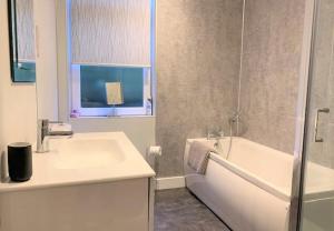 Un baño con bañera, lavabo y bañera. en Beach Apartment - Seafront Apartment, en Filey