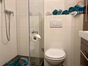a bathroom with a toilet and a glass shower at Landhaus Gertrude 106 - Wohnung Ida in Juist