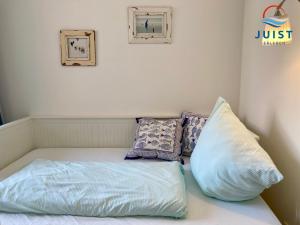 a bed with pillows sitting on top of it at Landhaus Gertrude 106 - Wohnung Ida in Juist