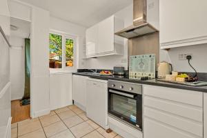 een keuken met witte kasten en een fornuis met oven bij Finest Retreats - White House Gardens in Southampton