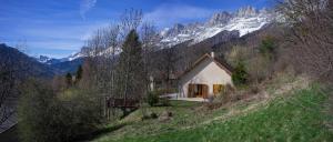 een klein huis op een heuvel met een besneeuwde berg bij Le Cerf d'Argent in Saint-Andéol