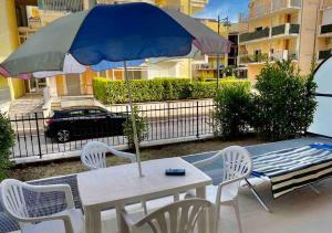 - une table et des chaises avec un parasol sur la terrasse dans l'établissement TORTORETO LIDO - Vista Mare-appartamento a mt100 dal mare, à Tortoreto Lido