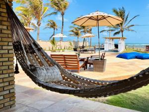 a hammock on a patio with a table and umbrella at Condado da Praia ,casa de temporada em Flecheiras-Ceará in Flecheiras