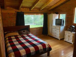 Dormitorio con cama y TV en una cabina en Casa de campo rústica en Cuenca, en Cuenca