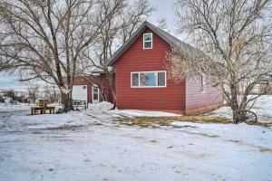 a red house with a bench in the snow at Charming Corral Creek Ranch House in Circle in Circle