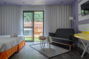 a bedroom with a bed and a couch and a chair at Logis Hôtel Domaine du Moulin Cavier - Restaurants & Spa in Avrillé