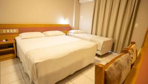a hotel room with two beds in a room at Hamburgo Palace Hotel in Balneário Camboriú